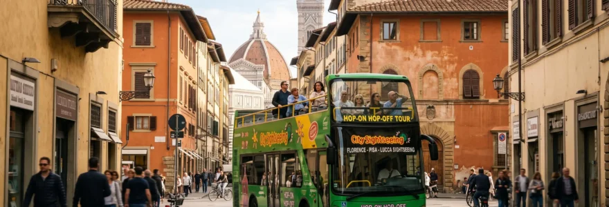 A green double-decker tour bus carrying passengers through a street in Florence with historic Tuscan buildings in the background.
